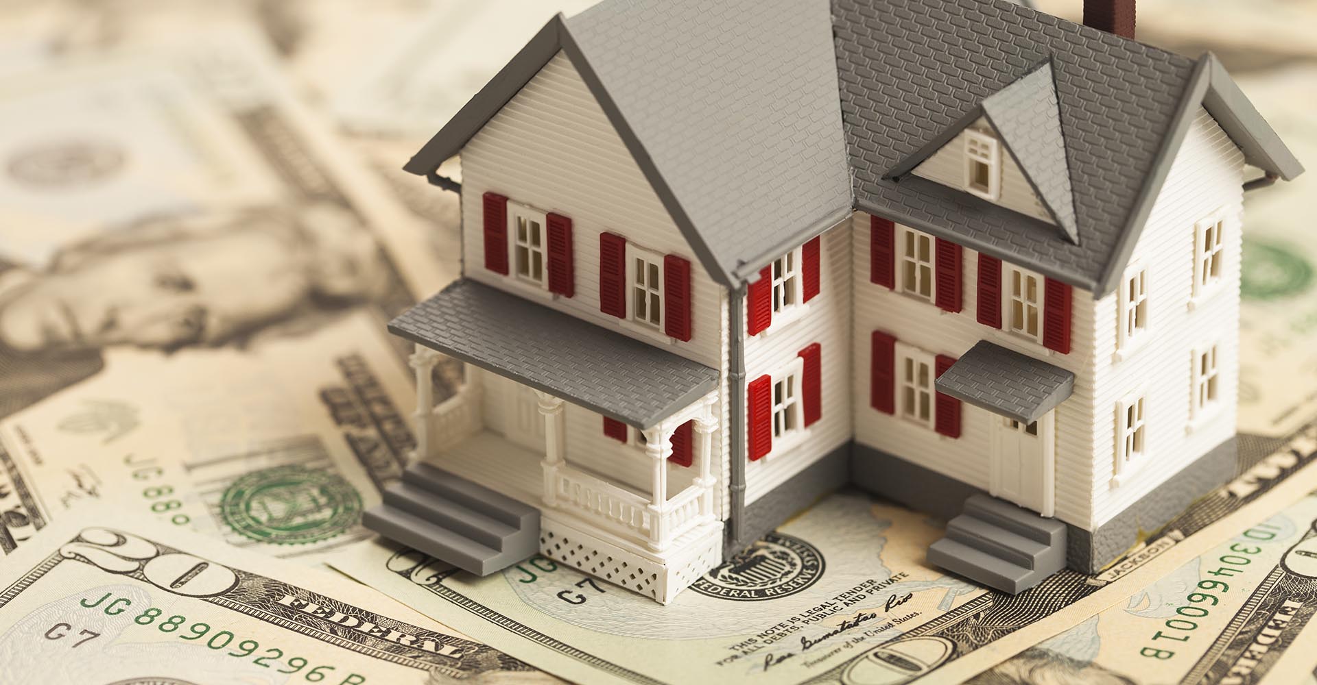 Model of a home sitting on a pile of cash
