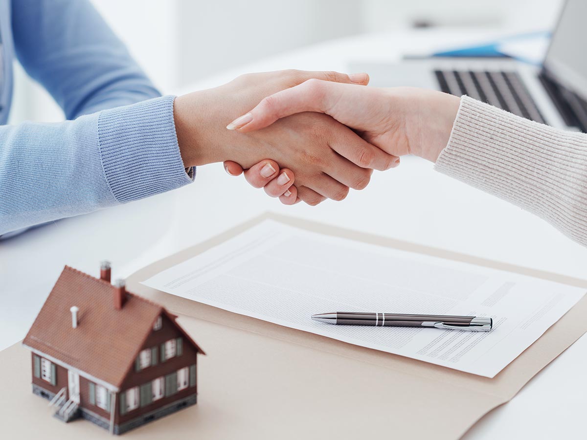 Two women shaking hands after signing home loan contract