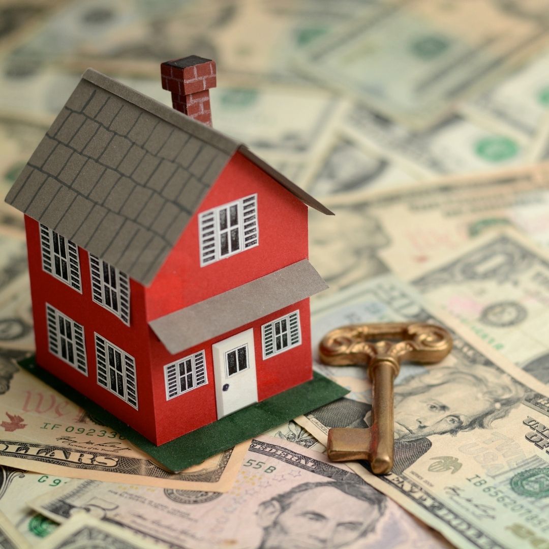 A toy house on top of a pile of money.