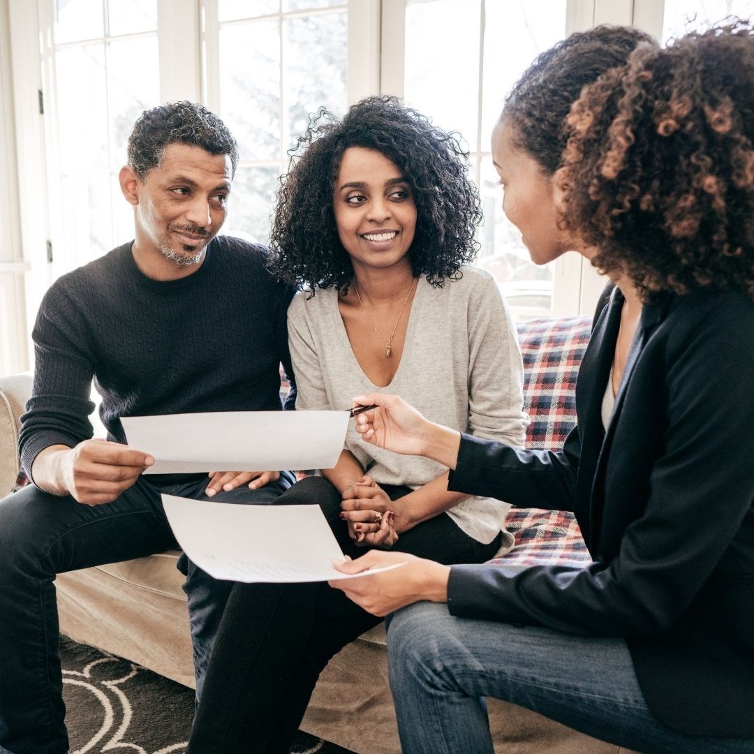 Happy couple and real estate agent going over paperwork