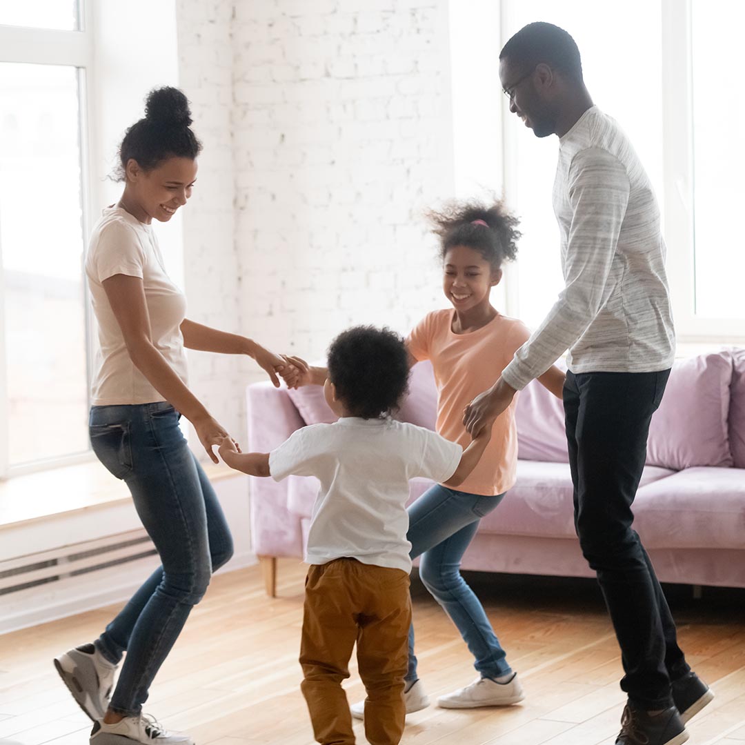 Happy family holding hands and dancing in living room