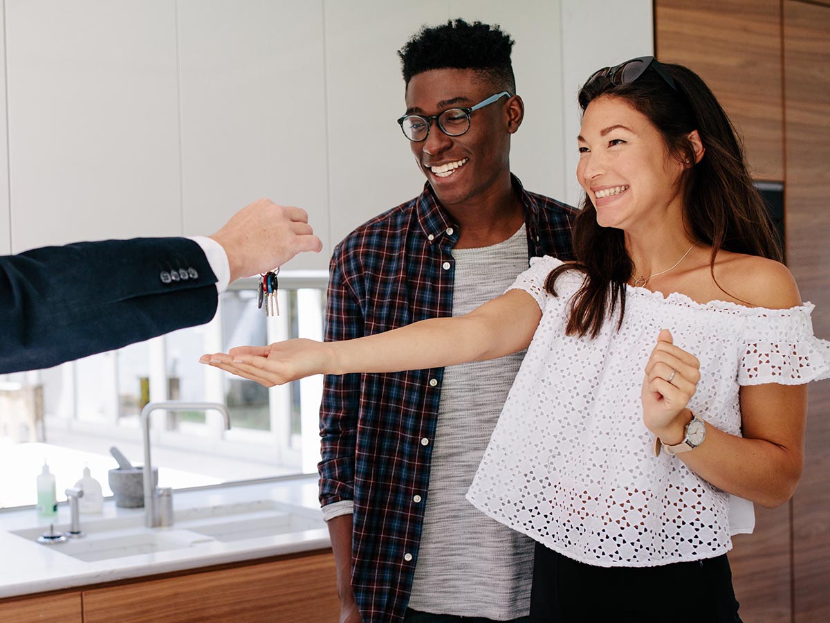 Realtor handing house keys to smiling couple