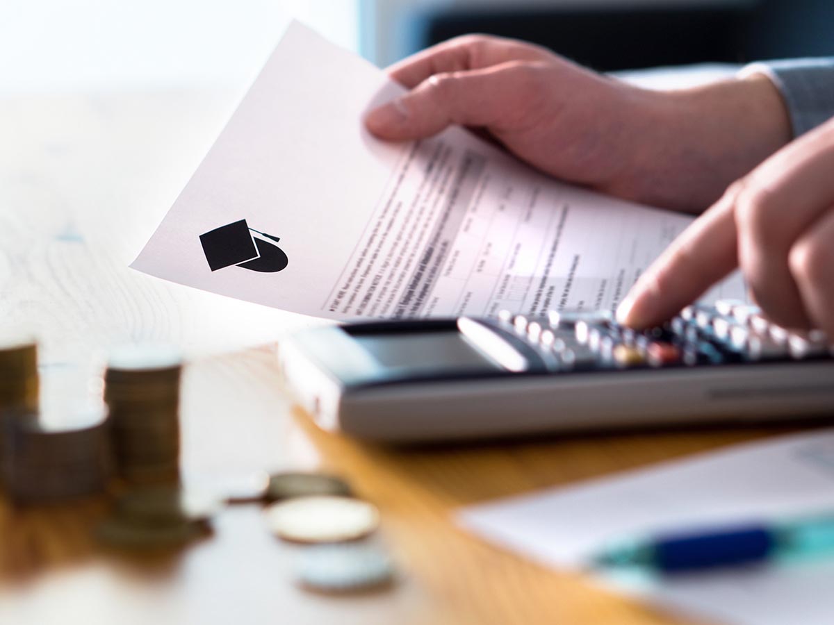 Person holding student loan bill and using a calculator