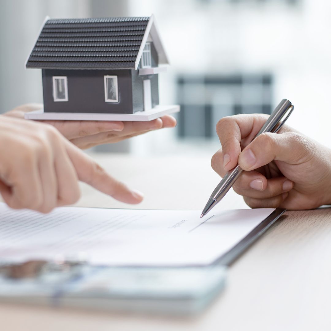 people signing paperwork with house motif