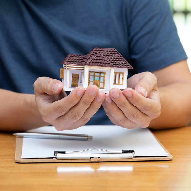 holding model house in hands, form with pen
