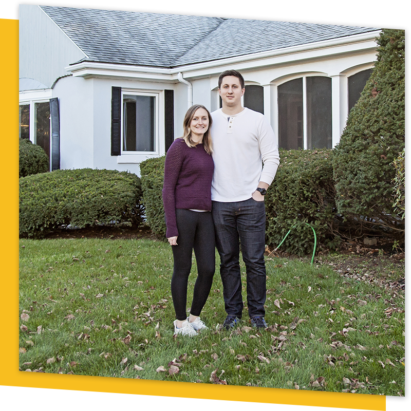 family smiling in front of house