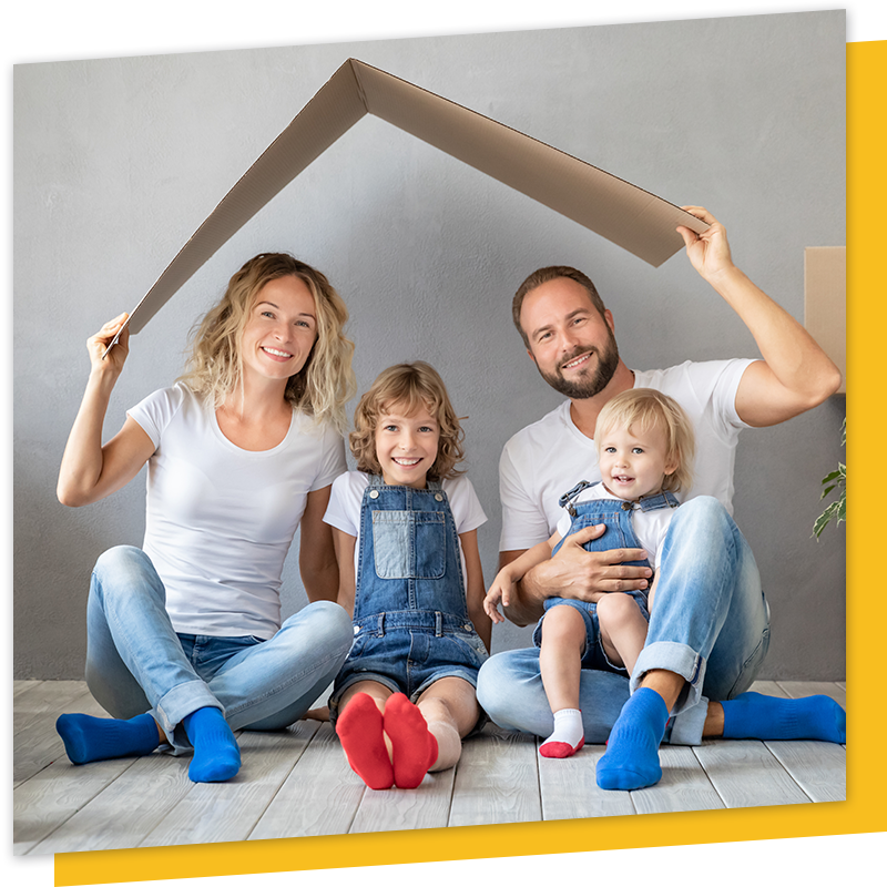 sitting family holding cardboard in roof shape, smiling