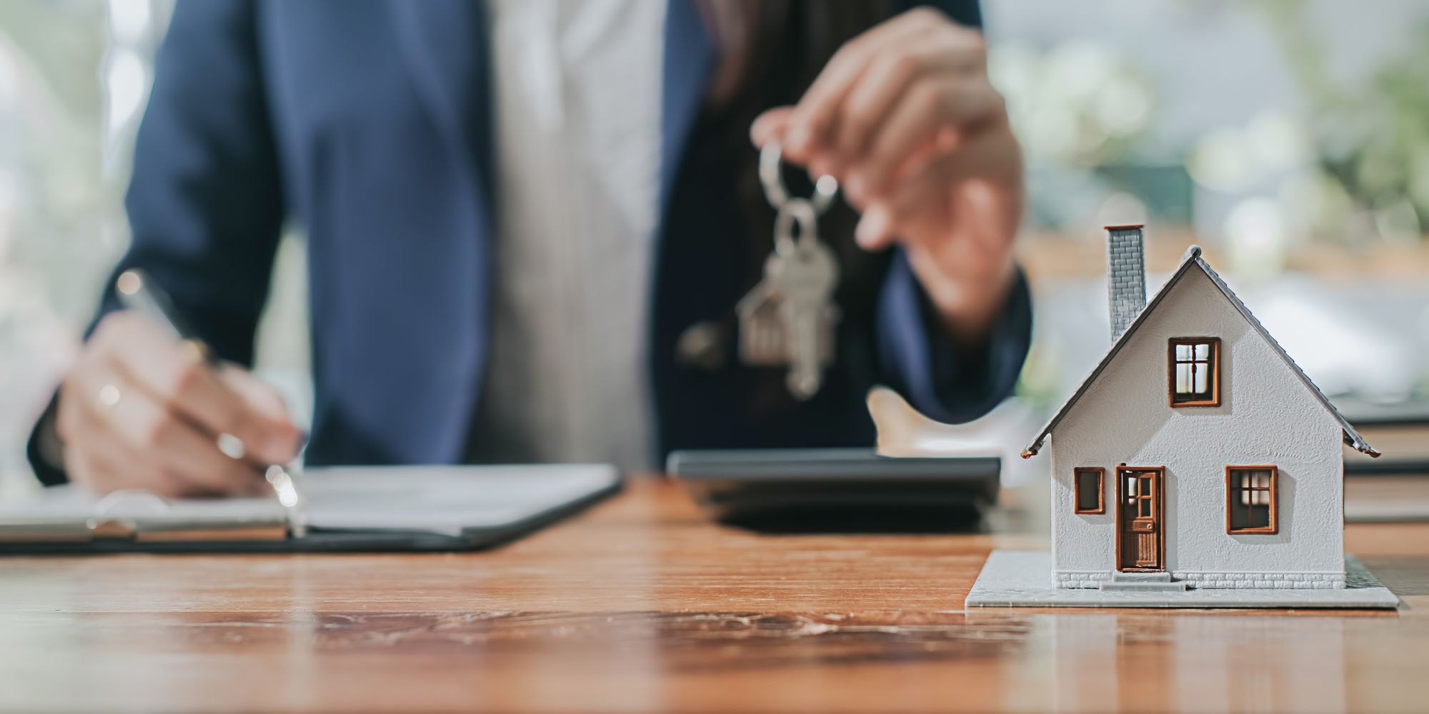 Person sitting at a desk holding a house key