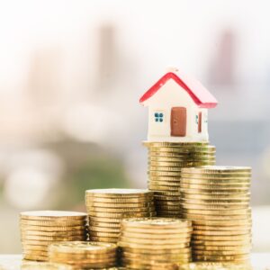 A house figurine on a stack of coins