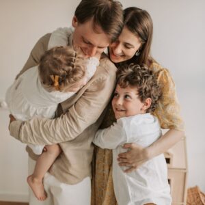 family wearing white and light colored clothes embraces for photo
