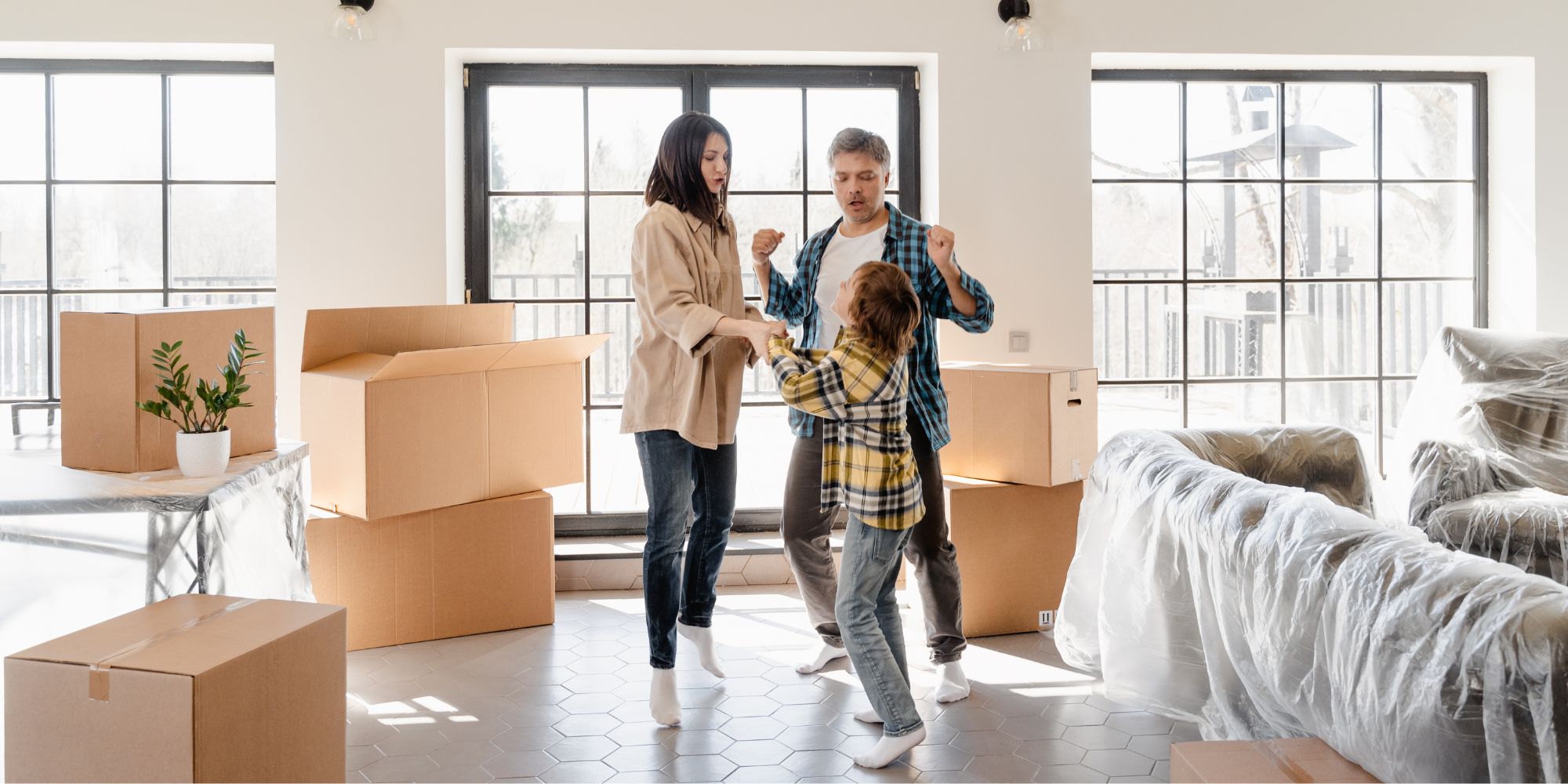 family dances in living room with moving boxes all around them